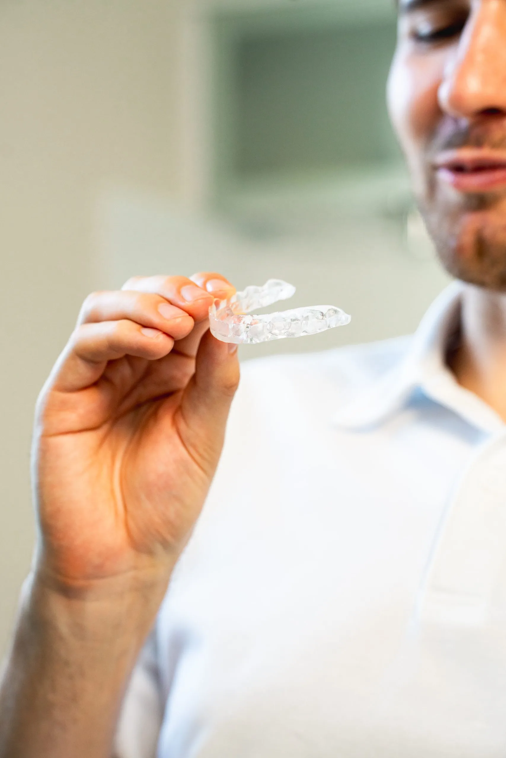 Patient hält transparente Zahnschiene in der Hand als Beispiel für moderne Schienentherapie